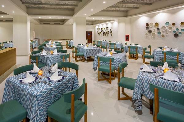 Innenbereich eines Restaurants im Grand Sirenis Punta Cana Resort mit blau-weißen Tischdecken und grünen Stühlen.