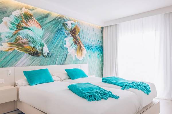 Schlafzimmer im Iberostar Waves Alcudia Park mit blauen Kissen und Bettwäsche auf weißen Betten.