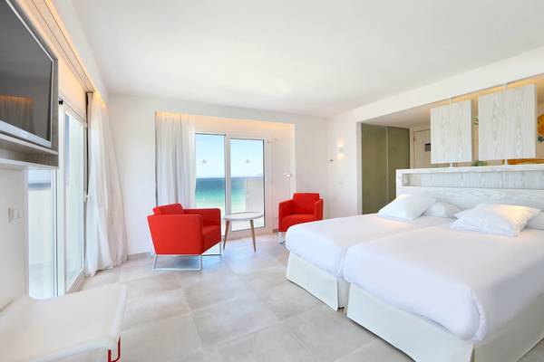 Innenansicht eines Hotelzimmers im Iberostar Waves Alcudia Park mit zwei Betten, roten Sesseln und einer Aussicht auf das Meer.