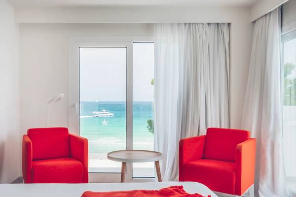 Hotelzimmer im Iberostar Waves Alcudia Park mit Meerblick und roten Stühlen.