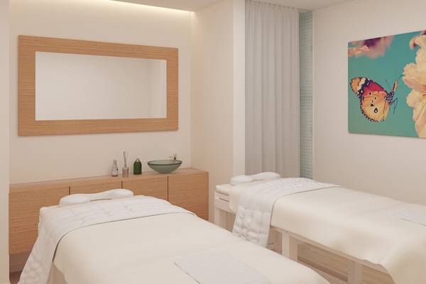 Spa-Behandlungsraum im Iberostar Waves Alcudia Park mit zwei Massagetischen, einem Wandspiegel und einer Wandmalerei mit Schmetterlingen.