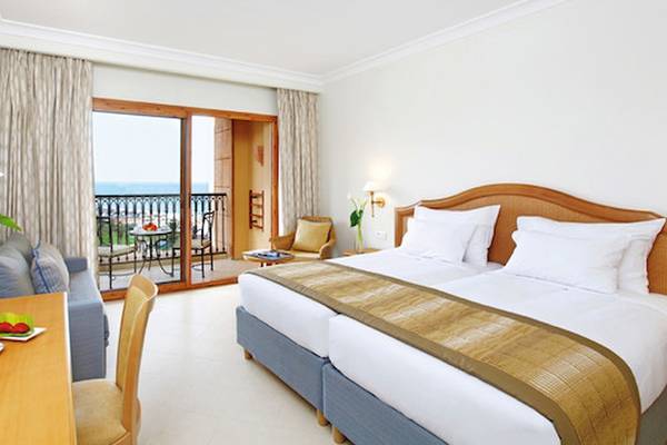 Hotelzimmer im Mövenpick Resort & Marine Spa Sousse mit Meerblick, Doppelbett, Balkon, Tisch und Sessel.