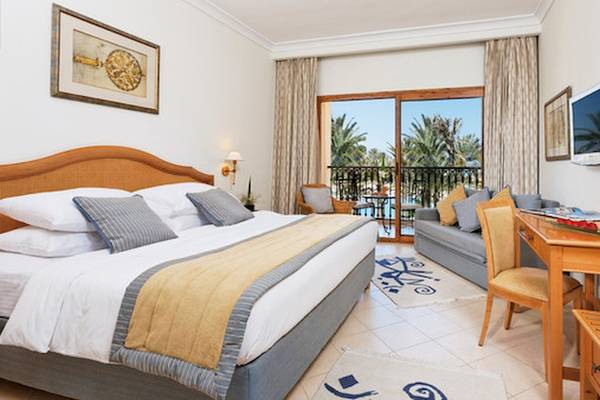 Hotelzimmer im Mövenpick Resort & Marine Spa Sousse mit großem Bett, Schreibtisch und Balkon.