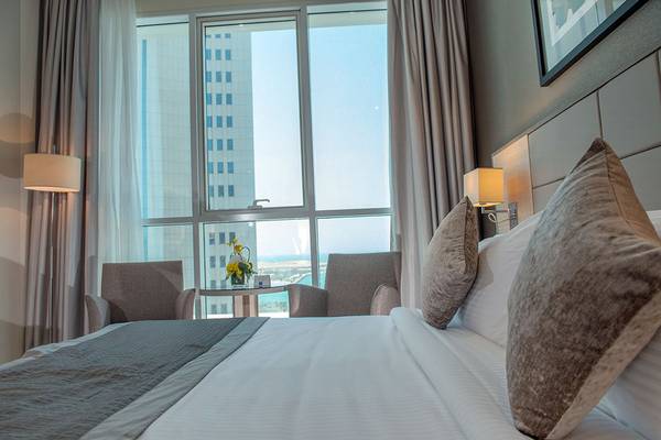 Hotelzimmer mit Bett, Sitzen, Tisch und Blick auf ein Gebäude.