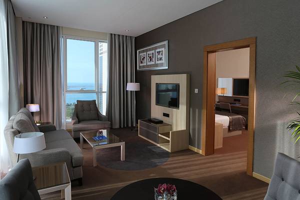 Wohnzimmer der Hotelsuite mit Blick auf das Meer im TRYP by Wyndham Abu Dhabi City Center.