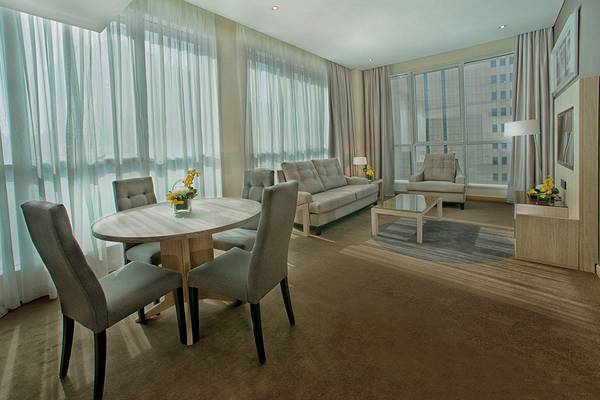 Wohnbereich im TRYP by Wyndham Abu Dhabi City Center mit Sofa, Esstisch und Fenstern.