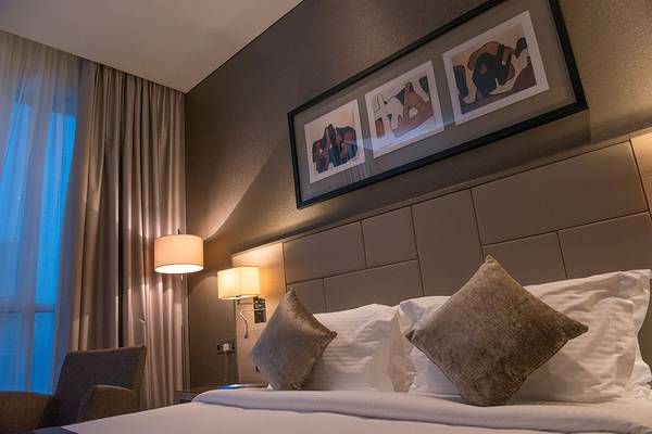 Hotelzimmer im TRYP by Wyndham Abu Dhabi City Center mit bequemem Bett, Kissen, Lampen und Kunstwerken an der Wand.