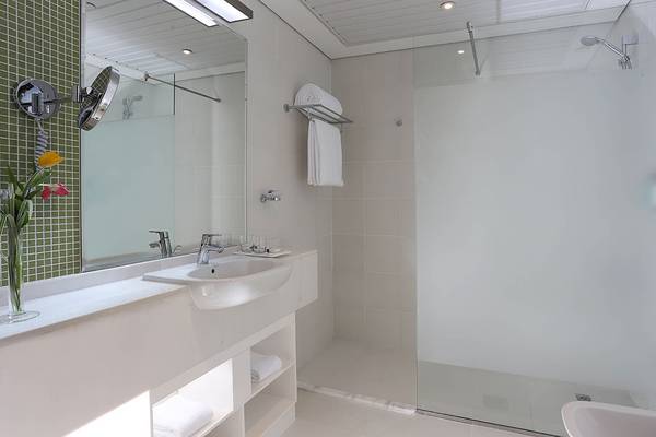 Badezimmer im TRYP by Wyndham Abu Dhabi City Center mit weißer Einrichtung, Spiegel und Dusche.