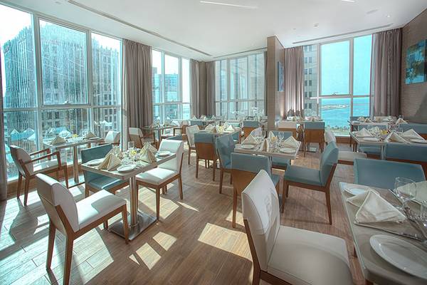 Innenansicht des Restaurants im TRYP by Wyndham Abu Dhabi City Center mit Blick auf die Stadt und das Meer.