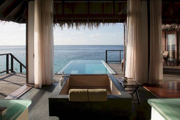 Innenansicht einer Suite im Coco Bodu Hithi mit Blick auf das Meer und einen Pool.