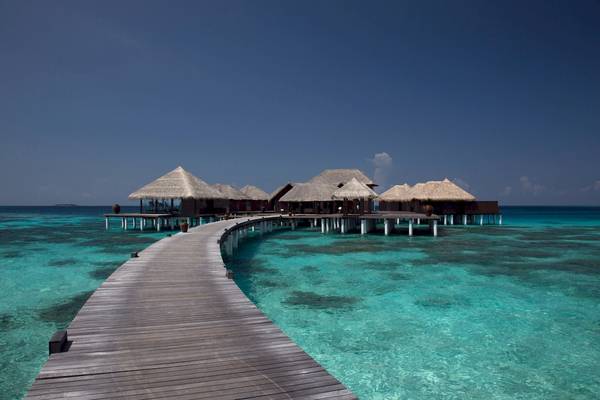 Coco Bodu Hithi Hotel über Wasser mit Steg und kleinen Hütten