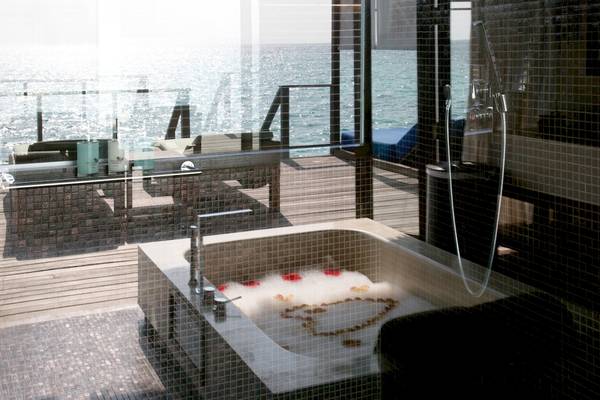 Badewanne im Coco Bodu Hithi Hotel mit Blick auf das Meer und einem Herz aus Rosenblättern