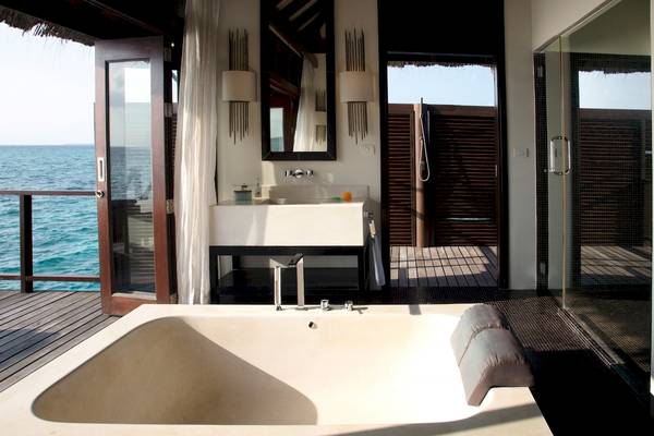 Badezimmer des Coco Bodu Hithi Hotels mit Blick auf das Meer von einer Überwasser-Villa.