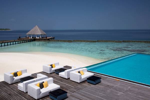 Terrasse des Coco Bodu Hithi Hotels mit weißen Sitzmöbeln und Infinity-Pool