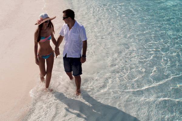 Paar am Strand im Coco Bodu Hithi Hotel, beide in der Brandung gehend