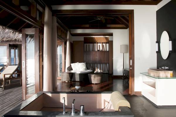 Innenansicht des Badezimmers im Coco Bodu Hithi Hotel mit Badewanne und offenem Zugang zur Terrasse.