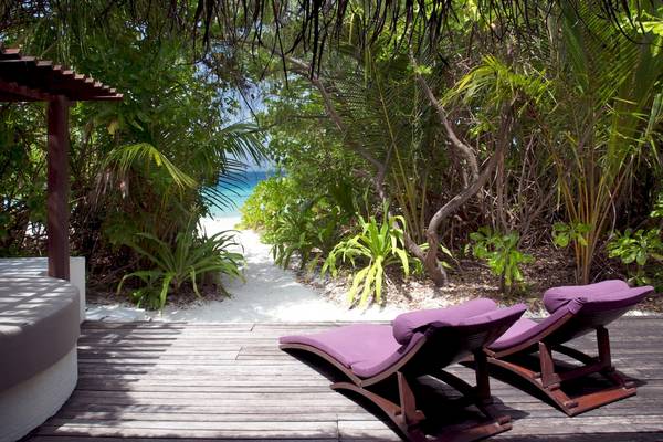 Coco Bodu Hithi Hotel Terrasse mit Lounge Stühlen und Blick auf den Strand