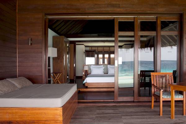 Zimmer im Coco Bodu Hithi Hotel mit Blick auf das Meer durch eine offene Tür.