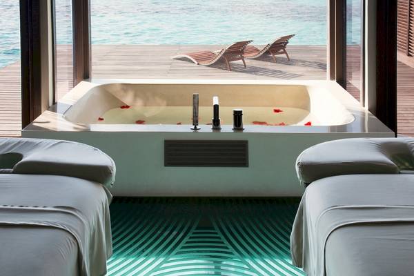Innenansicht des Coco Bodu Hithi Hotels mit Blick auf eine Badewanne und das Meer.
