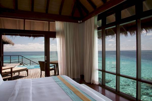 Ein Bett im Hotelzimmer von Coco Bodu Hithi mit großem Fenster und Meerblick.