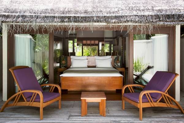 Ein Schlafzimmer mit zwei violetten Liegestühlen und einem Bett auf einer Terrasse.