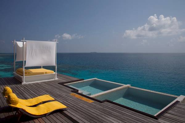 Terrasse des Coco Bodu Hithi Hotels mit Bett und Pool, Blick auf das Meer.