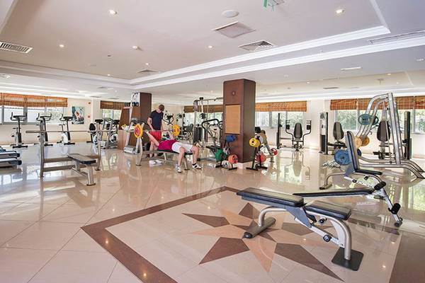 Fitness-Center im Hotel Club Nena mit verschiedenen Geräten und Menschen, die trainieren.