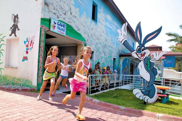 Kinder laufen vor einem Gebäude mit einer riesigen Bugs-Bunny-Figur und einer bunten Wandmalerei