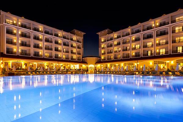 Nachtansicht des großen Swimmingpools des Paloma Oceana Hotels mit beleuchteten Gebäuden.