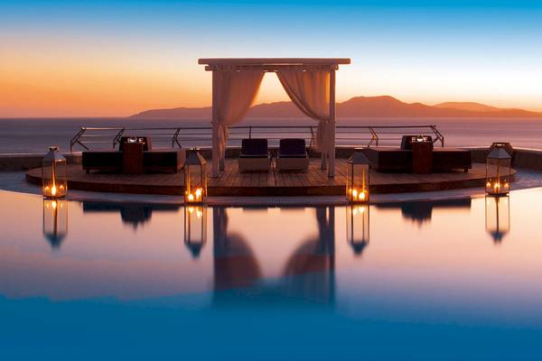 Abendstimmung am Infinity-Pool des Mykonos Grand Hotel & Resort mit Loungebereich und Blick auf den Sonnenuntergang.
