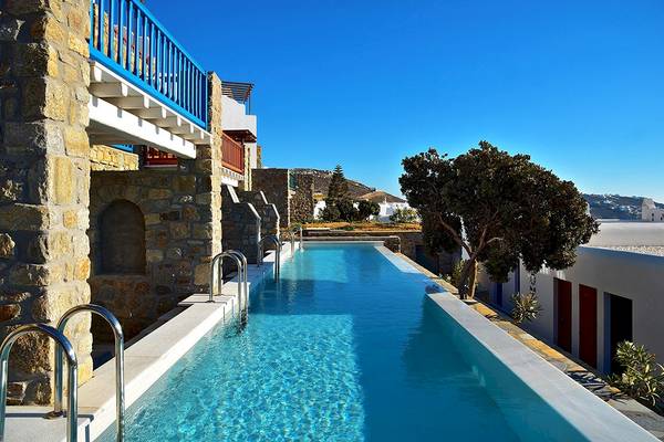 Außenpool des Mykonos Grand Hotel & Resort mit blauem Geländer und Steinmauern.