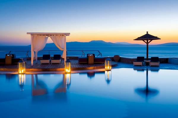 Sonnenuntergang am Pool des Mykonos Grand Hotel mit Loungemöbeln und Laternen