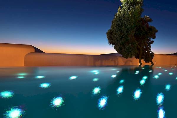 Außenpool des Mykonos Grand Hotel & Resort bei Nacht mit blauen Lichtern.