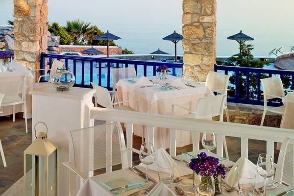 Außenterrasse des Mykonos Grand Hotels mit Tischen und Stühlen mit Blick auf das Meer