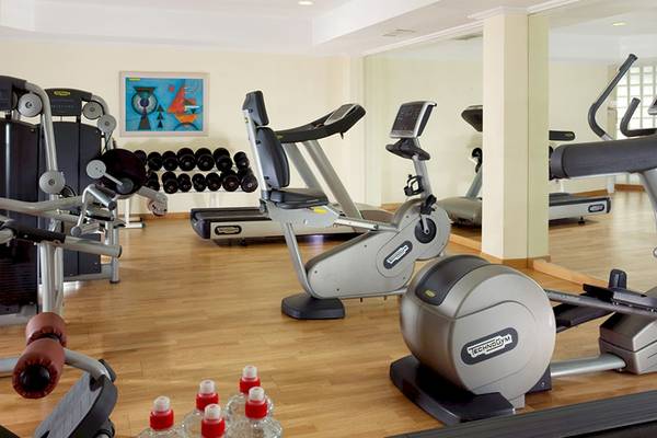Fitnessstudio im Mykonos Grand Hotel mit verschiedenen Geräten und einer gespiegelten Wand.