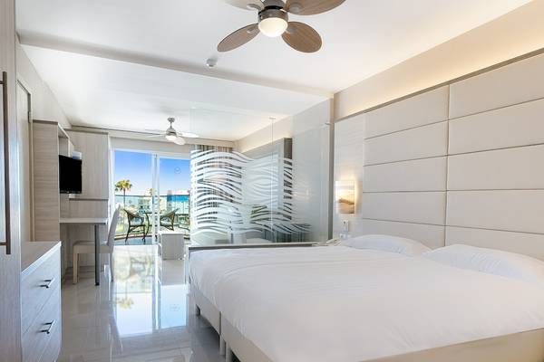 Modernes Hotelzimmer im Bull Dorado Beach & Spa mit Doppelbett, Fernseher und Schreibtisch.