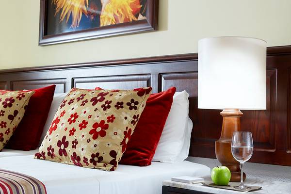 Bett im Albatros Spa & Resort mit Kissen, Lampen und Tisch mit Glas Apfel und Weinglas