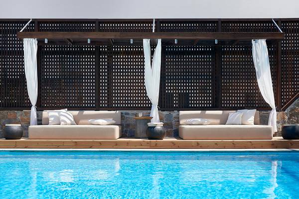 Pool-Loungebereich im Albatros Spa & Resort mit zwei Sitzgruppen, weißen Vorhängen und einem Pool.