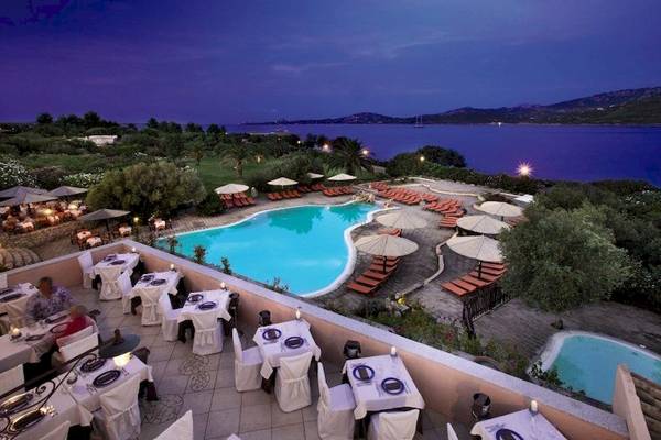 Luftaufnahme des Resort Cala Di Falco mit Swimmingpool, Liegestühlen und einem Blick auf das Meer.