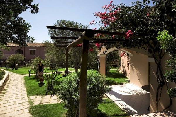 Außenbereich des Resort Cala Di Falco mit Gehweg, Pergola und Garten