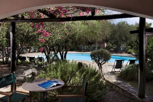 Aussicht auf den Pool im Resort Cala di Falco mit Lounge-Stuhl und Tisch.