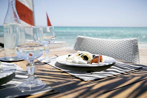 Tisch am Strand im Robinson Djerba Bahiya Hotel mit Gericht und Gläsern.