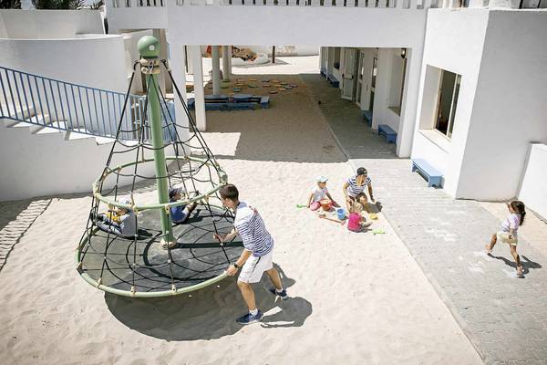 Kinder spielen im Sand mit einem Kletternetz im Robinson Djerba Bahiya Hotel.