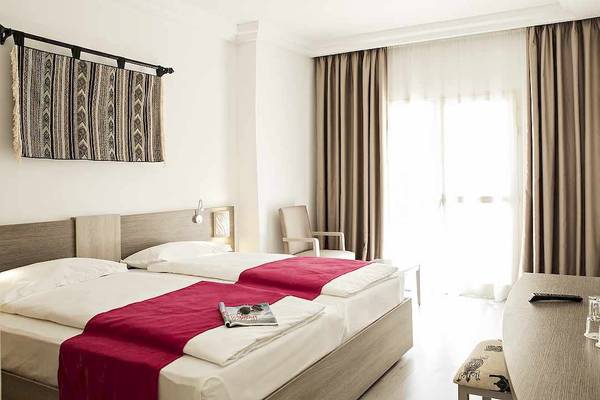 Zimmer im Robinson Djerba Bahiya Hotel mit zwei Betten, Dekor und Möbeln.
