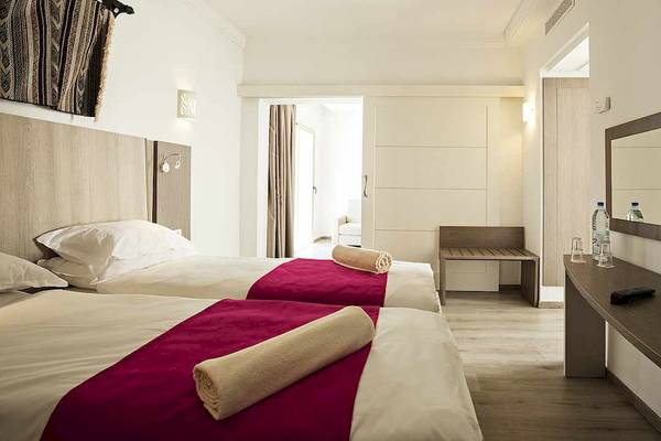 Zwei Doppelbetten mit roten Decken in einem Hotelzimmer im Robinson Djerba Bahiya.