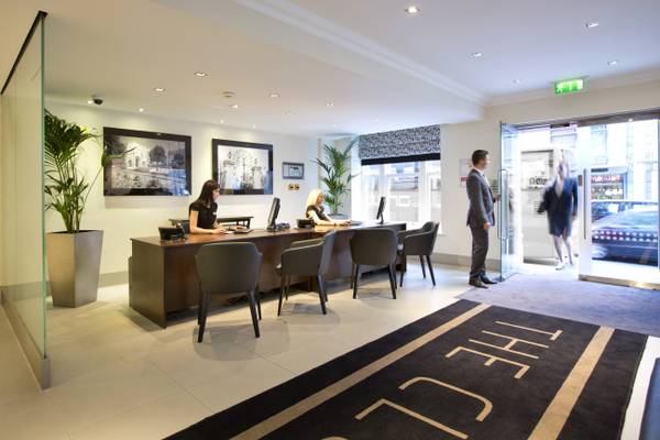 Empfangsbereich des The Cumberland Hotels mit Rezeptionistinnen und Gästen.