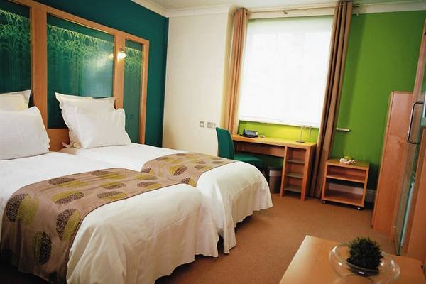 Doppelzimmer mit zwei Betten, grüne Wände, Schreibtisch und Fernseher.