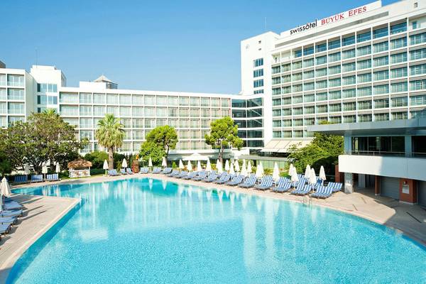 Außenbereich des Swissotel Buyuk Efes Izmir mit großem Swimmingpool und Sonnenliegen.