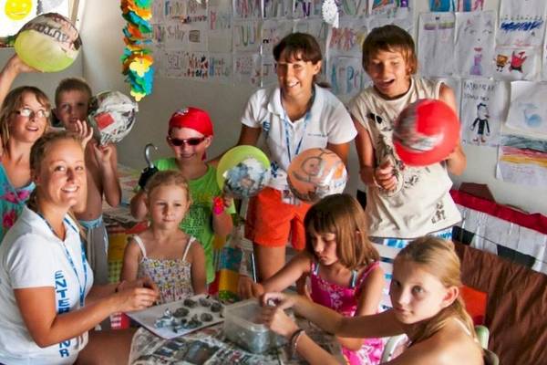 Gruppe von Kindern und Erwachsenen, die einen Workshop im Hotel Osmine Slano veranstalten, halten Ballons und malen.