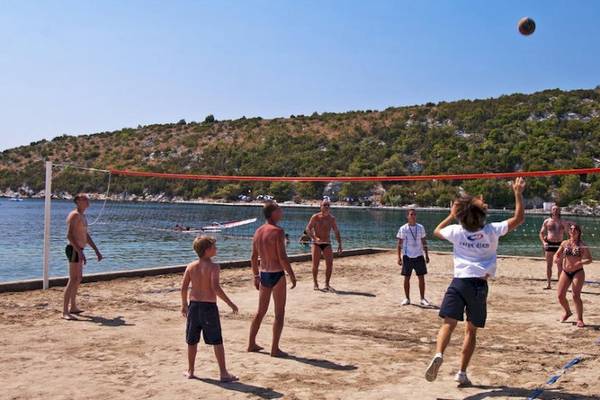 Mehrere Personen spielen Volleyball auf einem Strand in der Nähe des Osmine Slano Hotels.